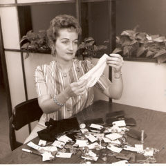 (FNB.2010.6.09) - First National Building Employee Examining Lost and Found Items, c. 1960