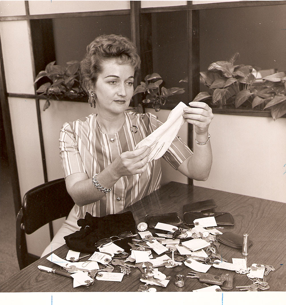 (FNB.2010.6.09) - First National Building Employee Examining Lost and Found Items, c. 1960